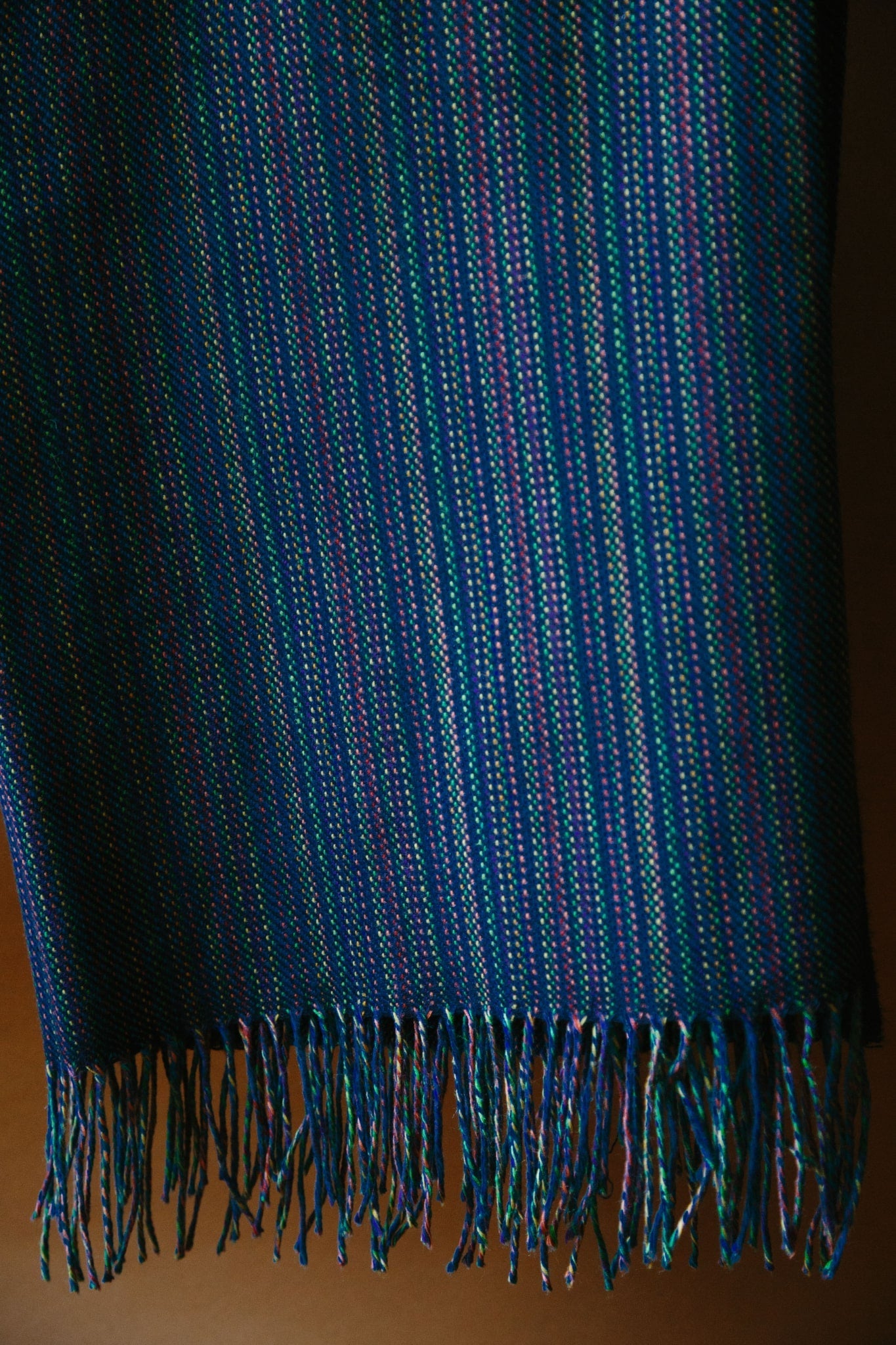 A deep navy merino throw. The shot has been taken close up so the weave structure can be seen. Multi coloured yarn has been used in the warp and a deep navy as the weft.