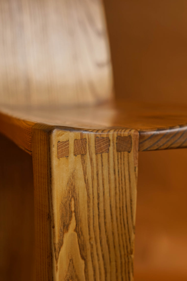Traditional joinery techniques on display at the join of the legs and seat on a 1970s elm high backed chair.