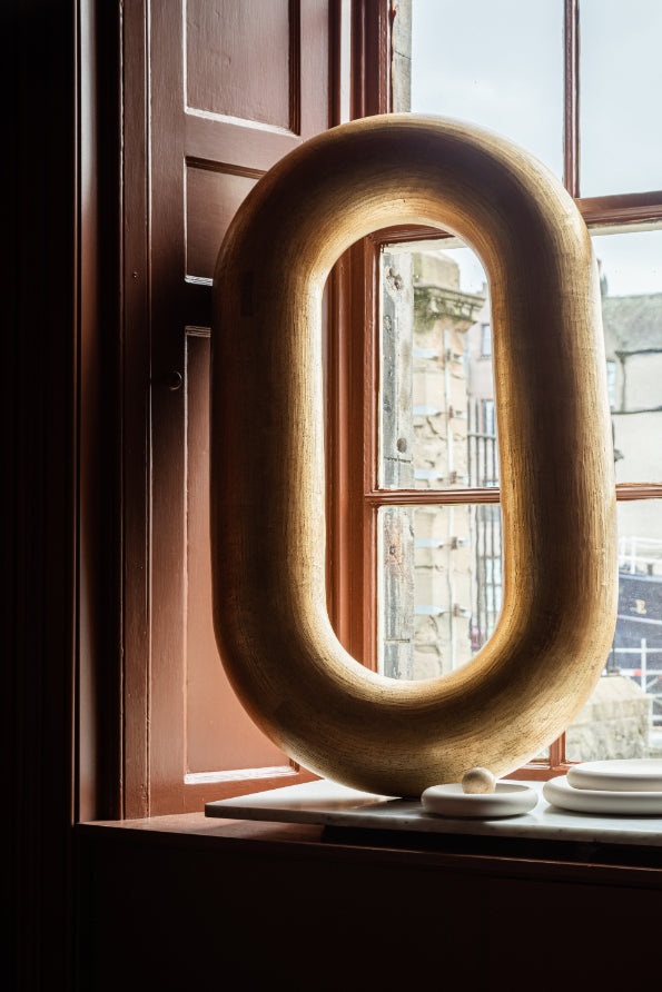 Large golden ceramic loop by James Rigler. A sculptural piece, pictured here in the window of Bard. A Leith based shop and gallery celebrating Scottish craft.