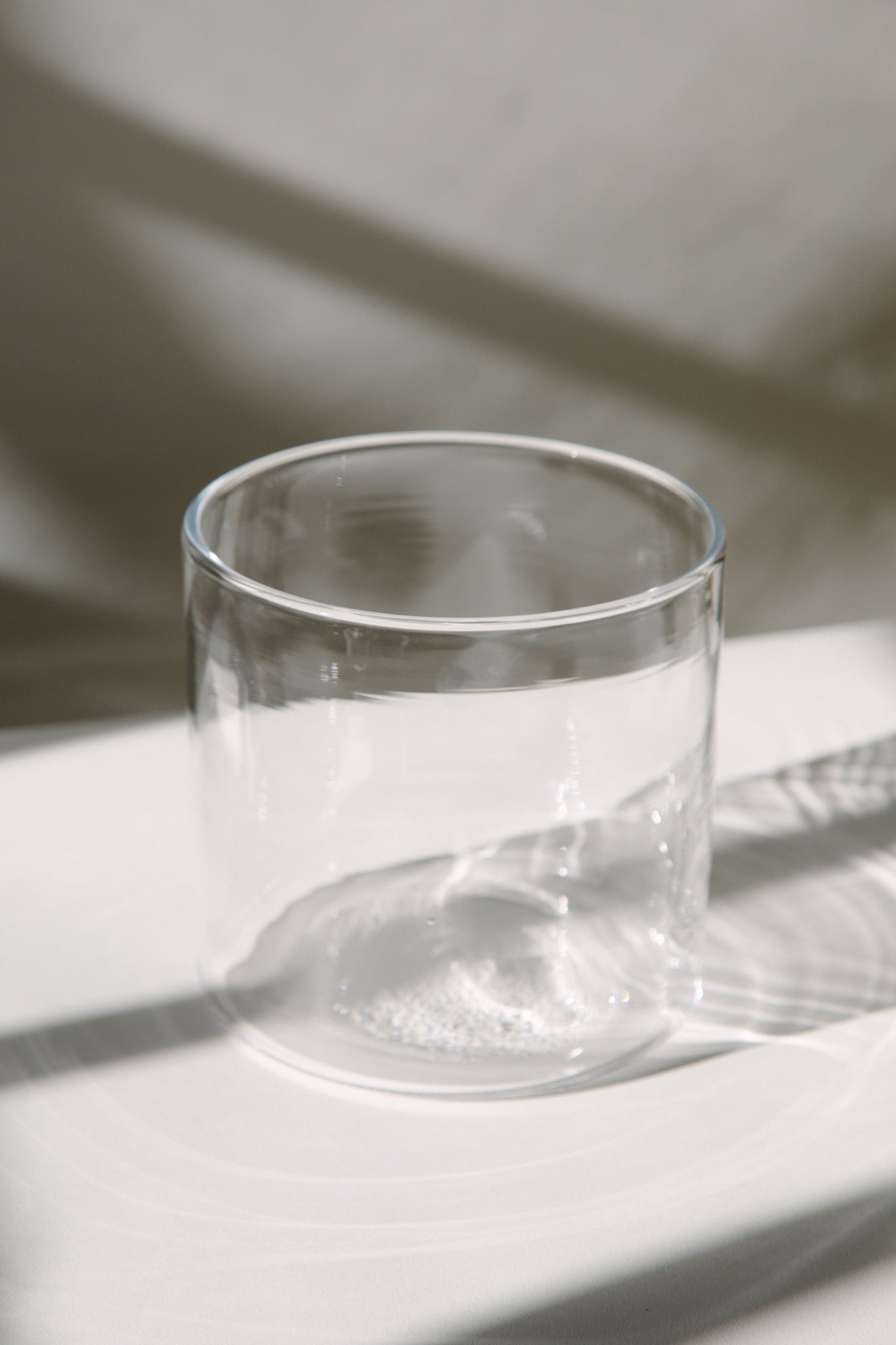Cylindrical glass vase shot on a white table top. Shot here empty.