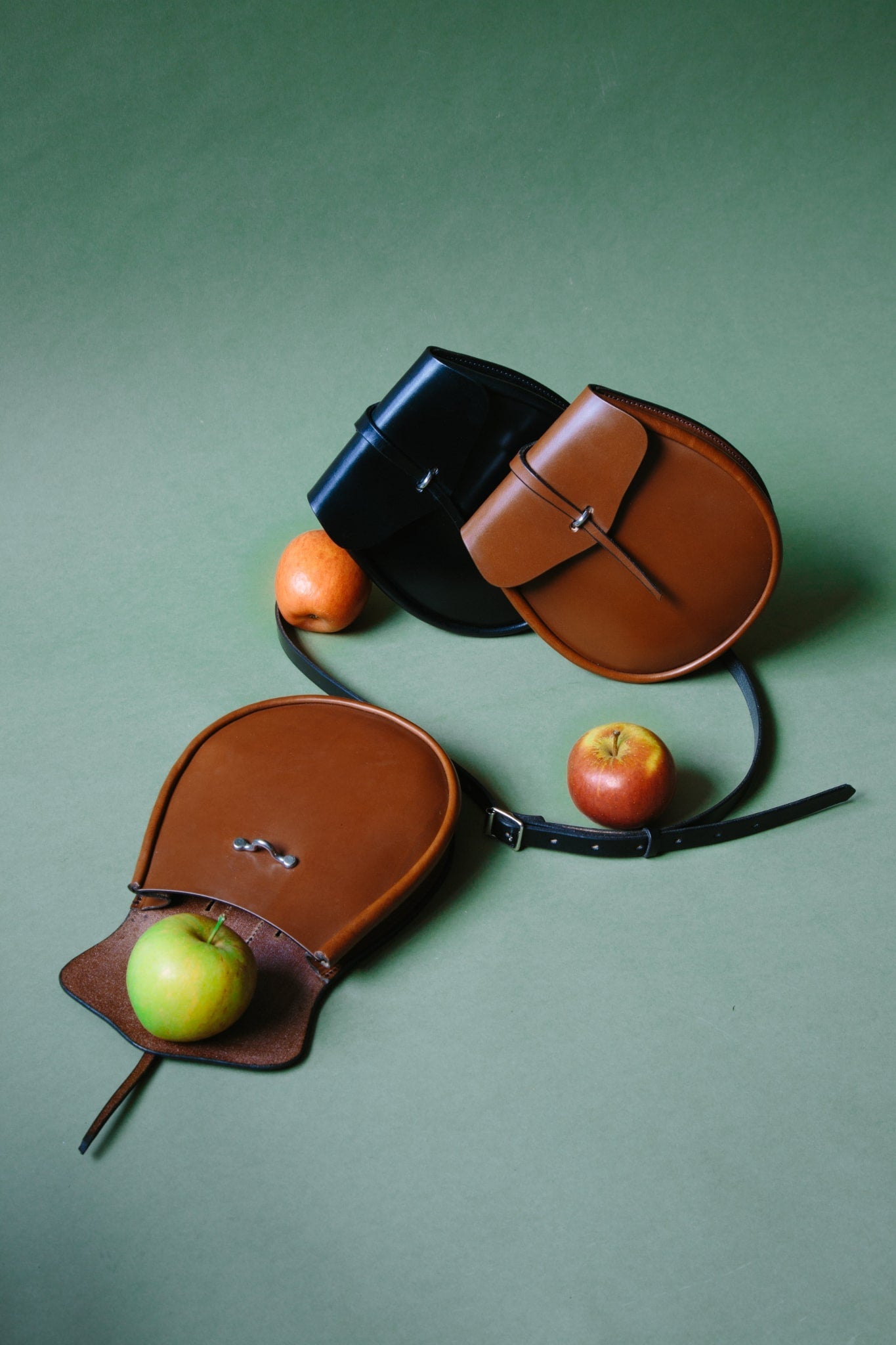 A group of three leather sporrans, one opened with an apple falling out. 