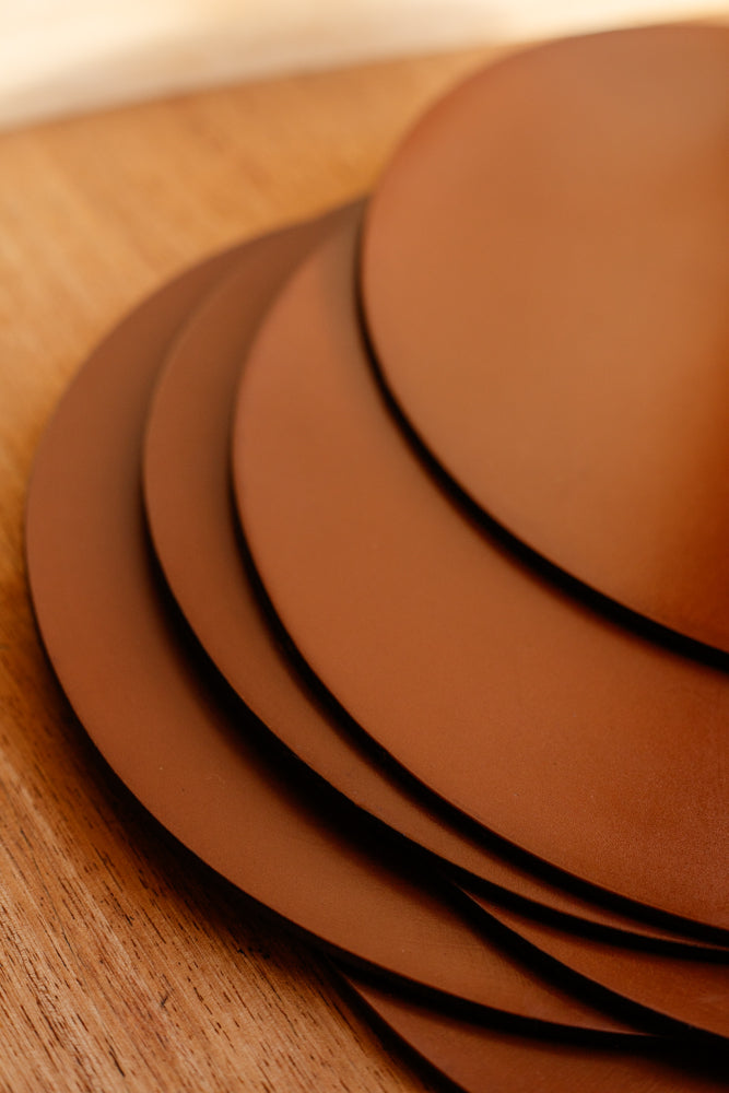 Close up shot of a stack of leather placemats from McRostie Leather placemats in tan. Shot at Bard Scotland, a shop and gallery in Leith.