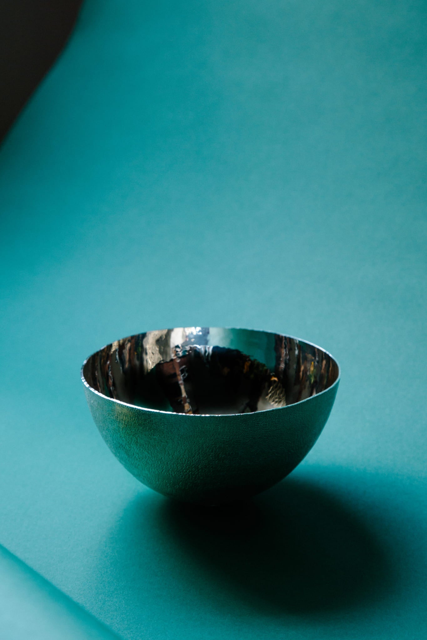 Hand-raised sterling silver bowl. Textured outer with a highly reflective inner surface. Beautifully delicate yet bold. Shot on a deep green paper backdrop.