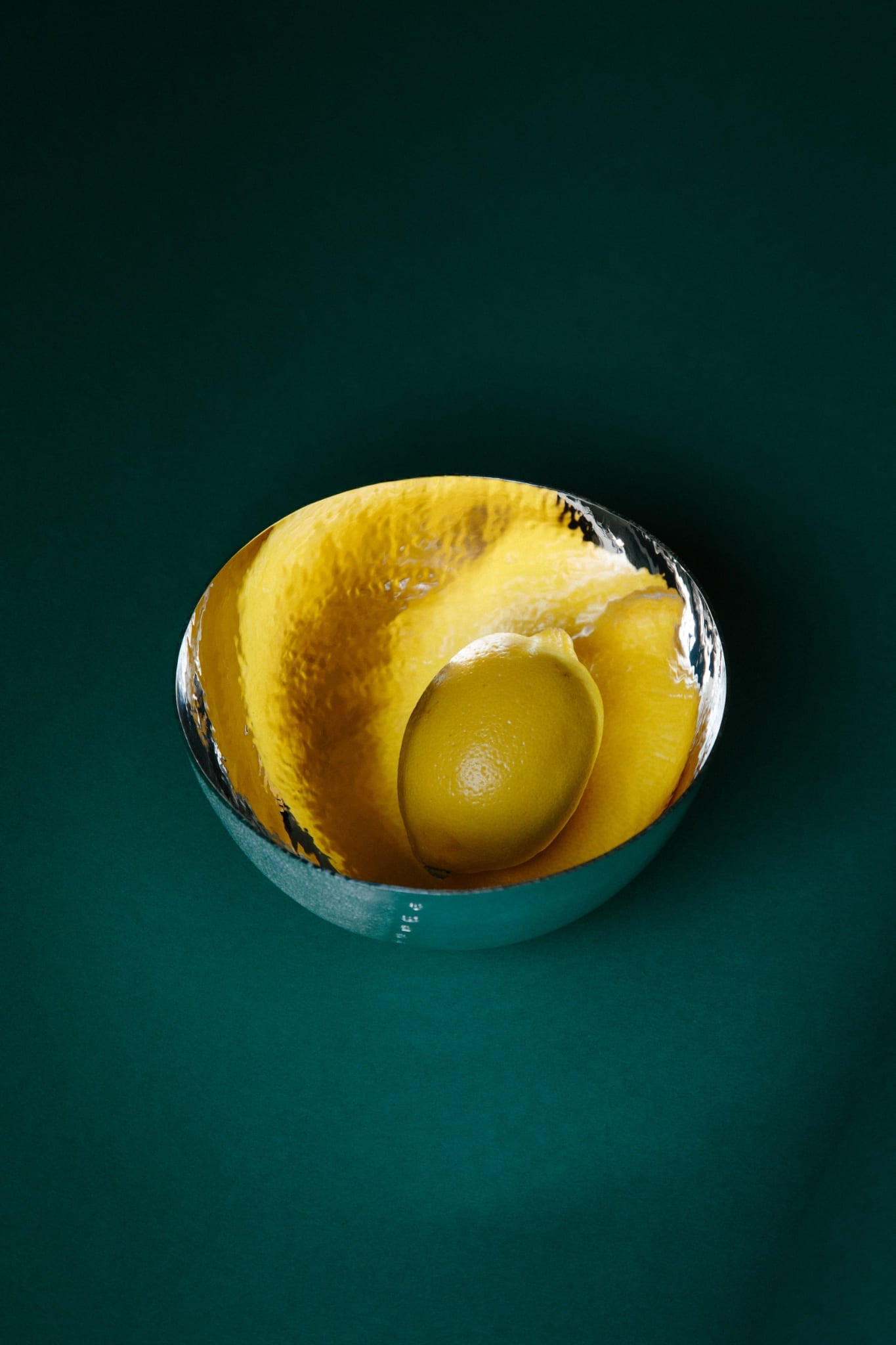 A bright dimpled lemon demonstrates the reflective inner surface of a sterling silver bowl.