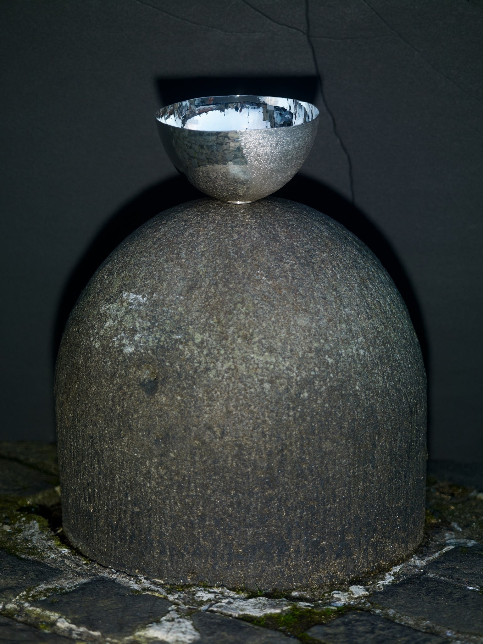 Sarah Cave Hand Raised Sterlign Silver Bowl balanced on a stone bollard with geometric shadow.