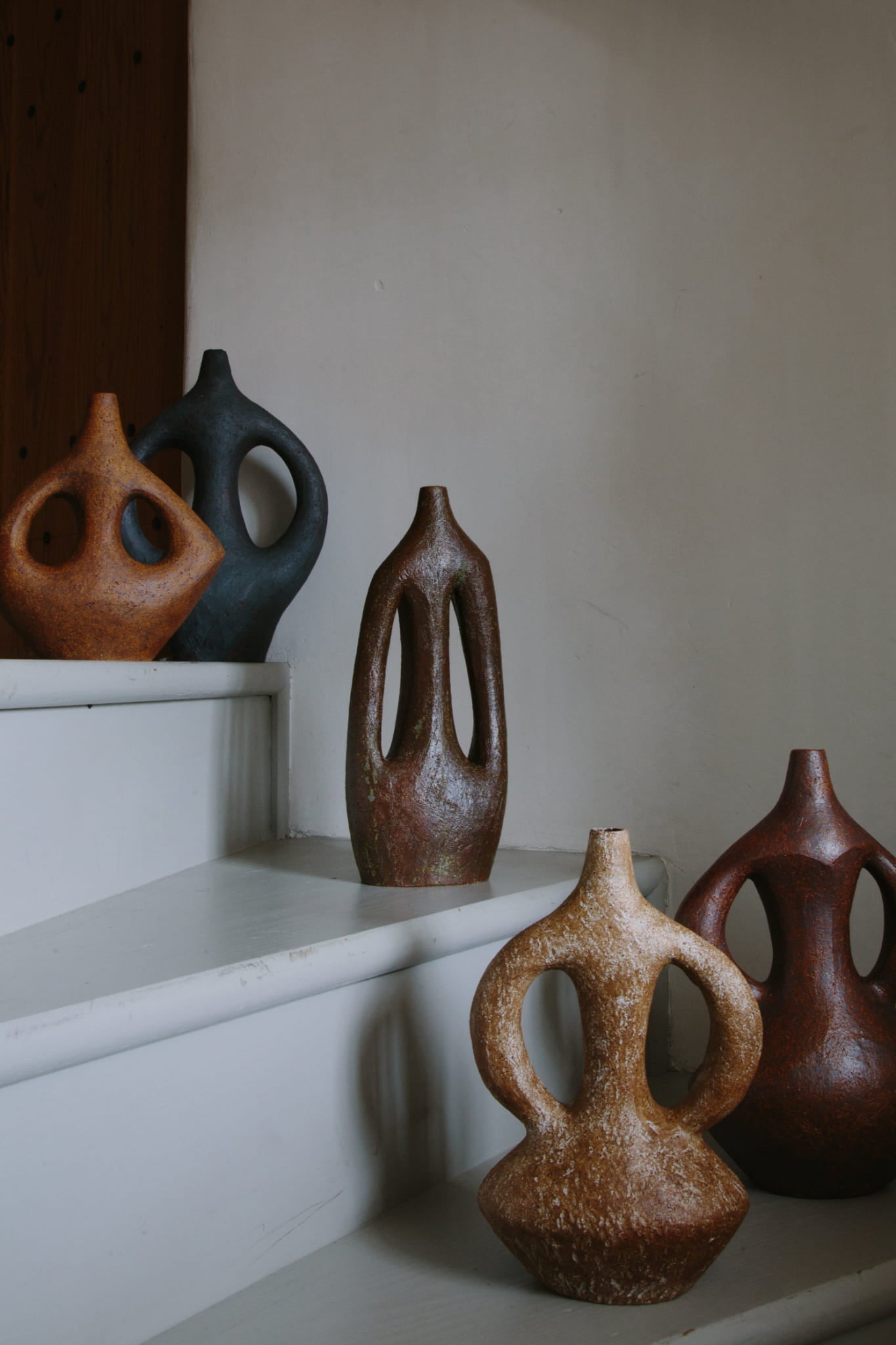 A series of five stoneware coil built vases by Viv Lee. Each with two handles, in a variety of figurative forms and deep earth toned clays and glazes.