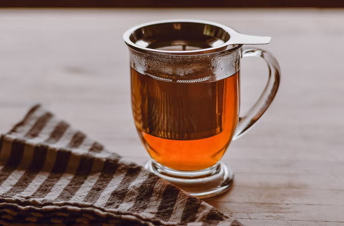 Rooibos tea infusing in a glass cup