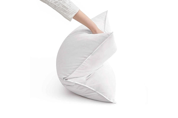 Close-up of a hand pressing into a pillow insert to demonstrate its softness and support.