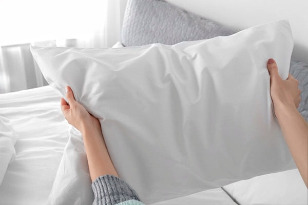 Person fluffing a pillow to maintain its shape.