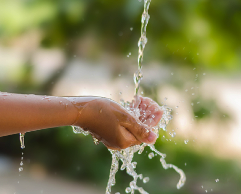 Mano tocando agua limpia y un fondo de naturaleza