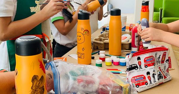 Niños pintando termos alxedo de color amarillo