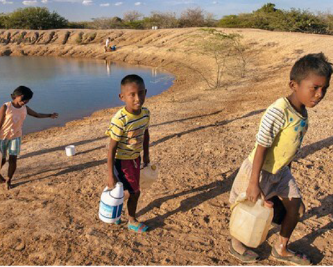 Tres niños acarreando agua de un lago