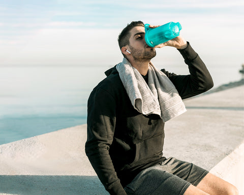 Hombre bebiendo agua después de hacer ejercicio y está cerca de la bahía.
