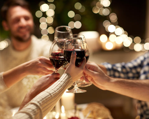 Personas brindando con sus copas de vino tinto.