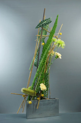 A container based floral design, with the materials positioned towards one side of the container to help create an asymmetrical feeling.