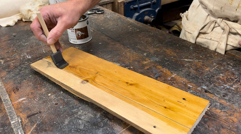 applying hard wax oil along the grain of pine wood