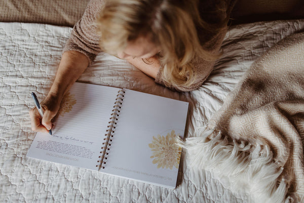 Woman Using Journal Prompts to Identify Root of Negative self-talk in JMB Living Journal