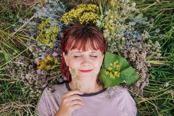 woman smiling, laying in grass among wildflowers