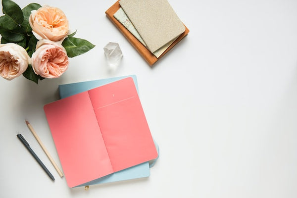 Journals next to flowers to cultivate self-love