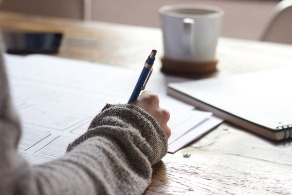 Woman journaling with a drink to practice positivity for self-love