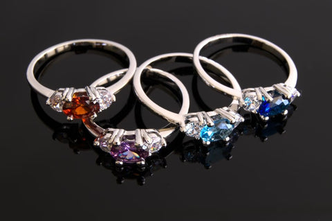 Black background with red, purple, and blue birthstone rings