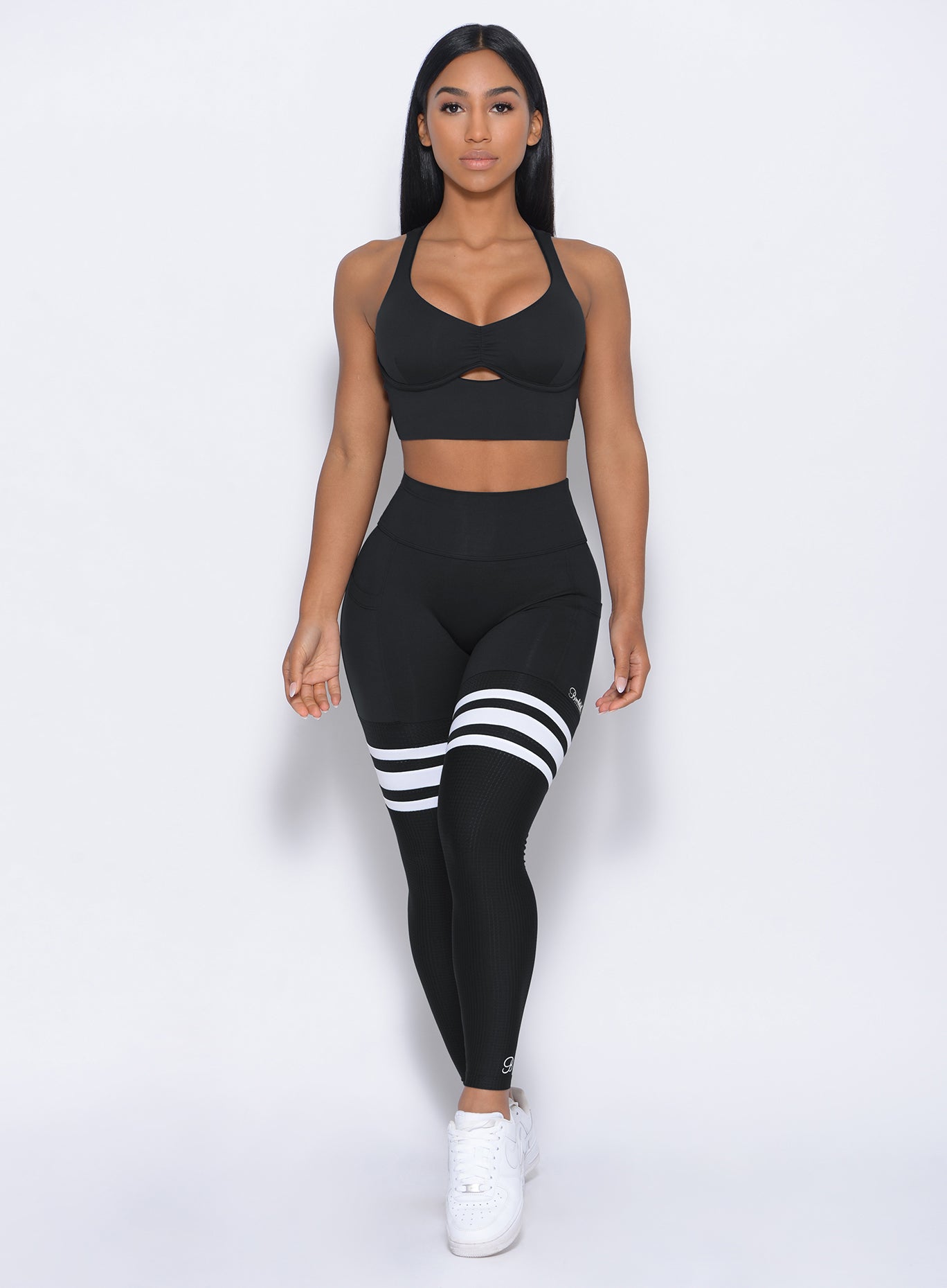 Front profile view of a model wearing our black perform thigh high leggings and a matching bralette 