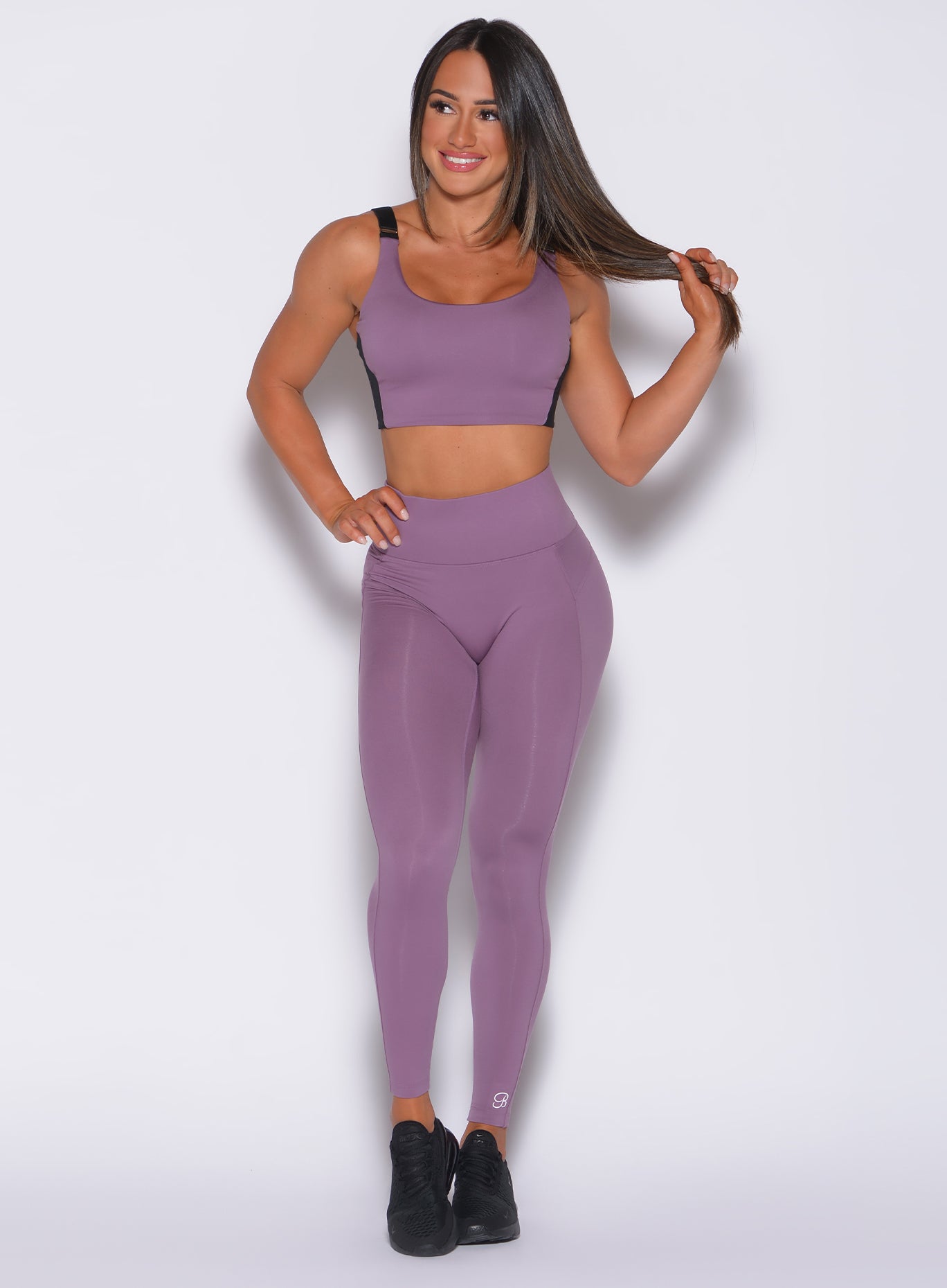 Front profile view of a model in our snatched waist leggings in violet frost color and a matching bra