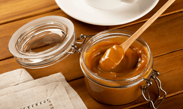Dulce de leche jar with a wooden spoon
