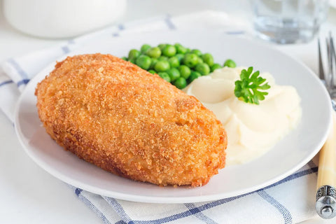 A plate with breaded chicken, mashed potatoes, and peas