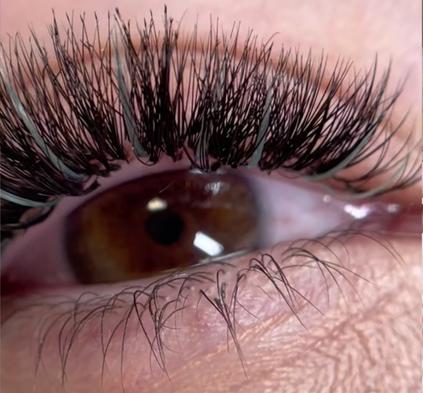 A photo showing a set of volume eyelash extensions with pale blue spikes. On the very tips of the lashes, there is some singing due to the model having lit cigarettes between the set being applied and the videos being taken. This was shot using a macro lens which is designed to take very close up images, the singed lash tips weren't very visible to the naked eye | London Lash Canada