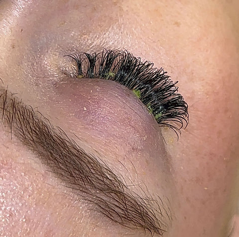 a set of lash extensions with green residue around the roots