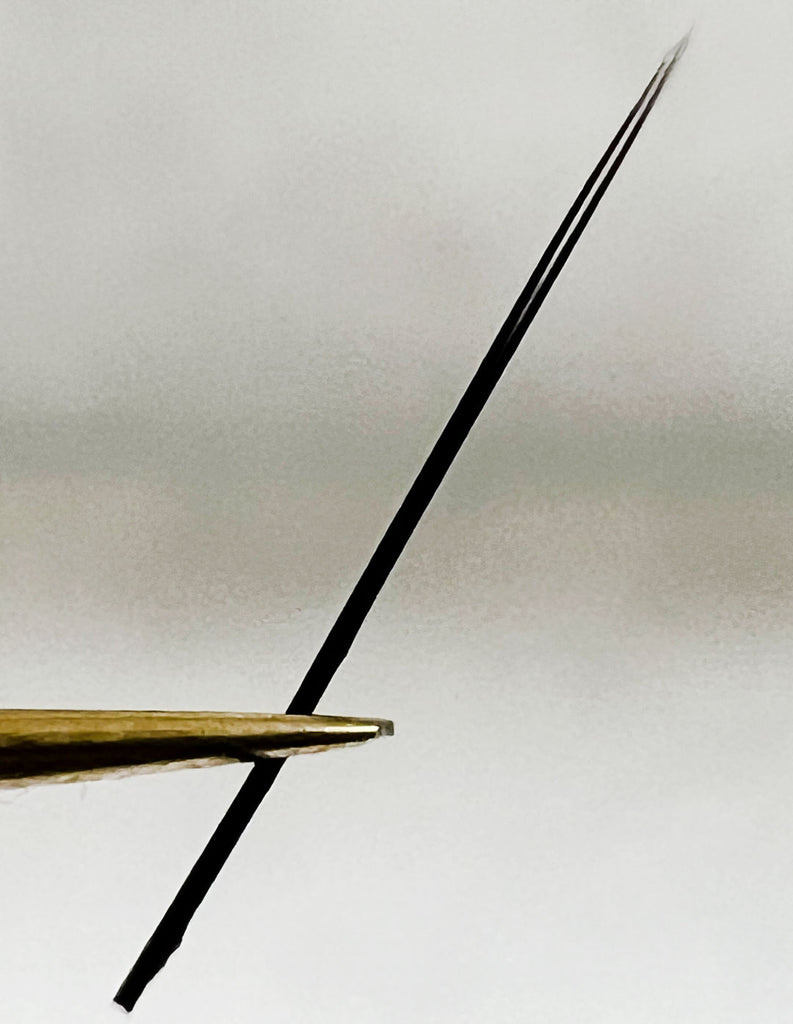 a close up of a flat lash held in a pair of tweezers showing the split in the tip