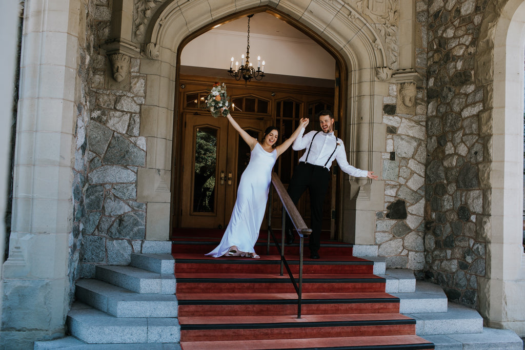 bride and groom celebrating outside of an old stone building entranceway