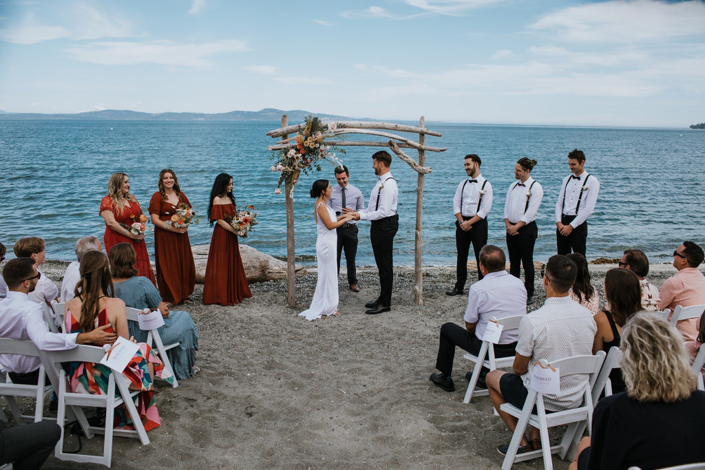 ceremony taking place on a sandy beach with blue ocean in the background
