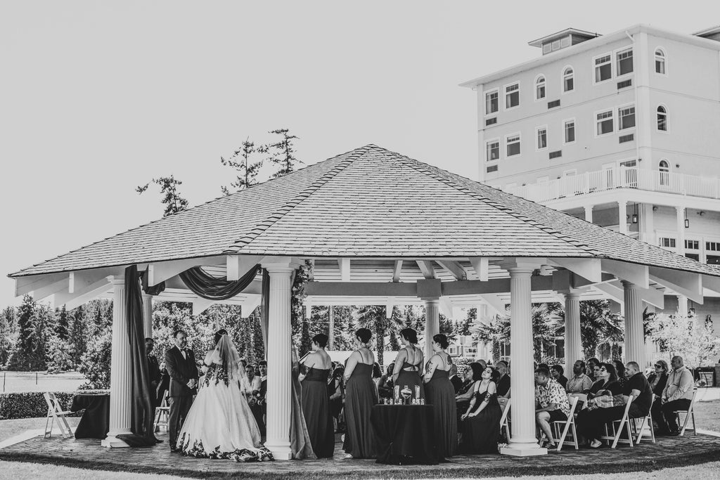wedding ceremony taking place under a large white pavilion gazebo in front of a hotel
