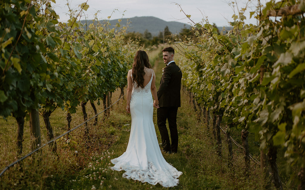 bride and groom walking through a vineyard