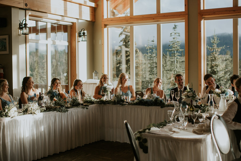 wedding party around a u-shaped table in front of a large window