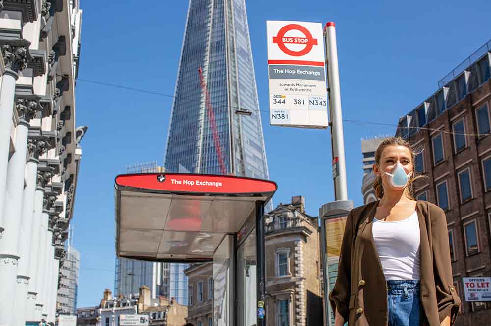 young lady wearing breathe happy commuter face mask next to bus stop in London