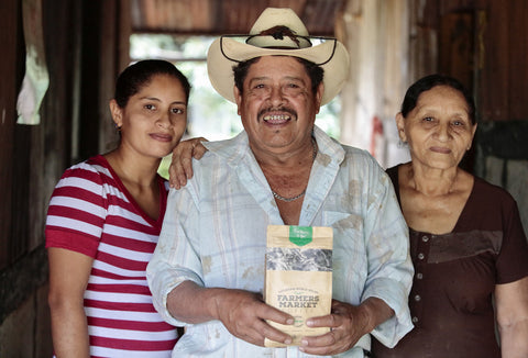Coffee Farmer Holding a Bag of Medium Roast Family, surrounded by his family.