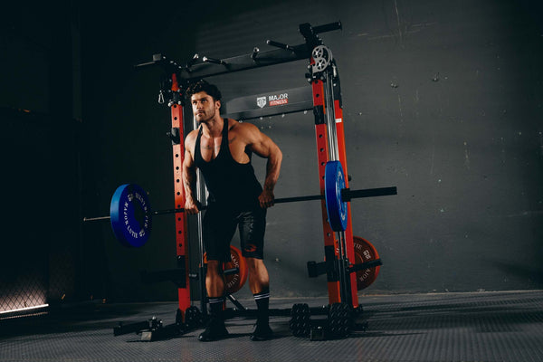 Man performing a deadlift with a barbell loaded with blue weight plates in a home gym.