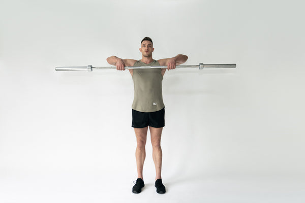 Man performing a barbell upright row with perfect form, a compound exercise targeting shoulder and upper back muscles