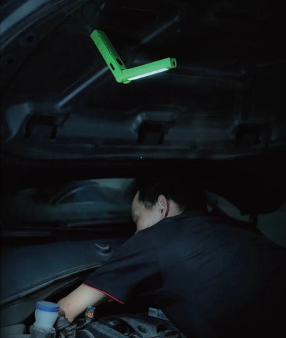 Mécanicien travaillant sous le capot avec une lampe de poche Realite