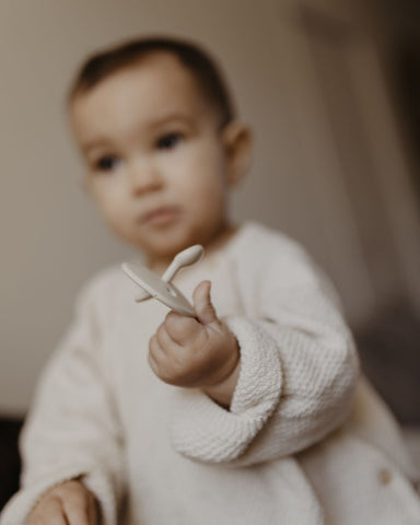 bébé qui tient une tétine dans la main 