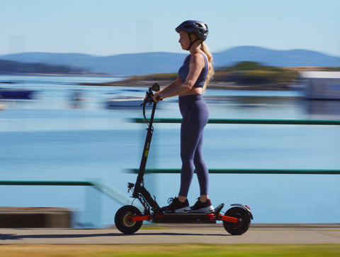 woman riding e-scooter with helmet in daylight