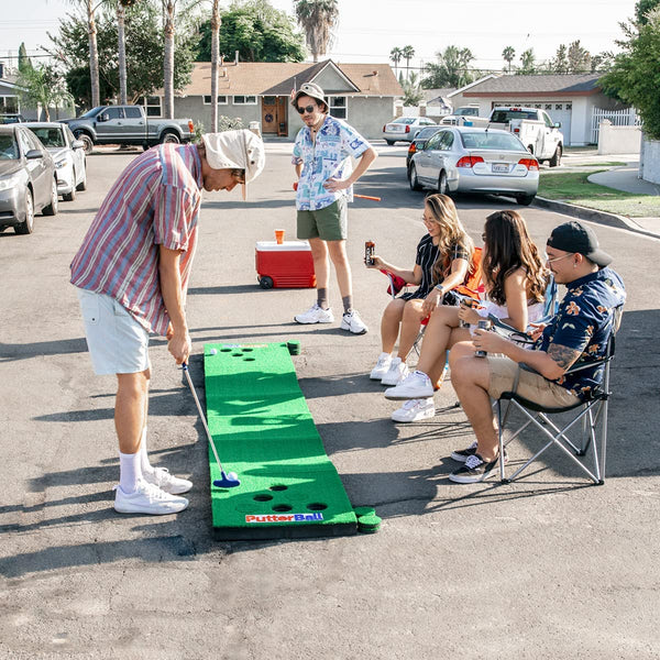 Friends hanging out outside playing Putterball a fun yard game that combines golf & beer pong