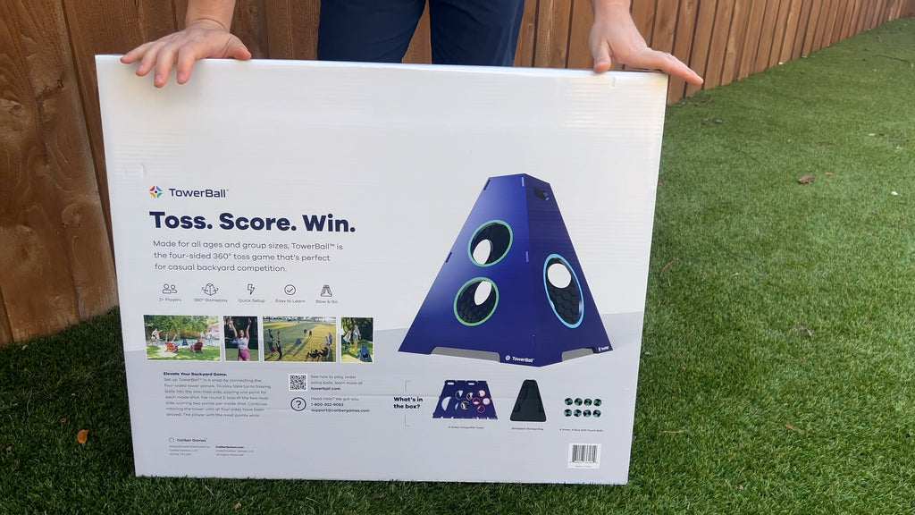 Person stands in backyard holding TowerBall box.