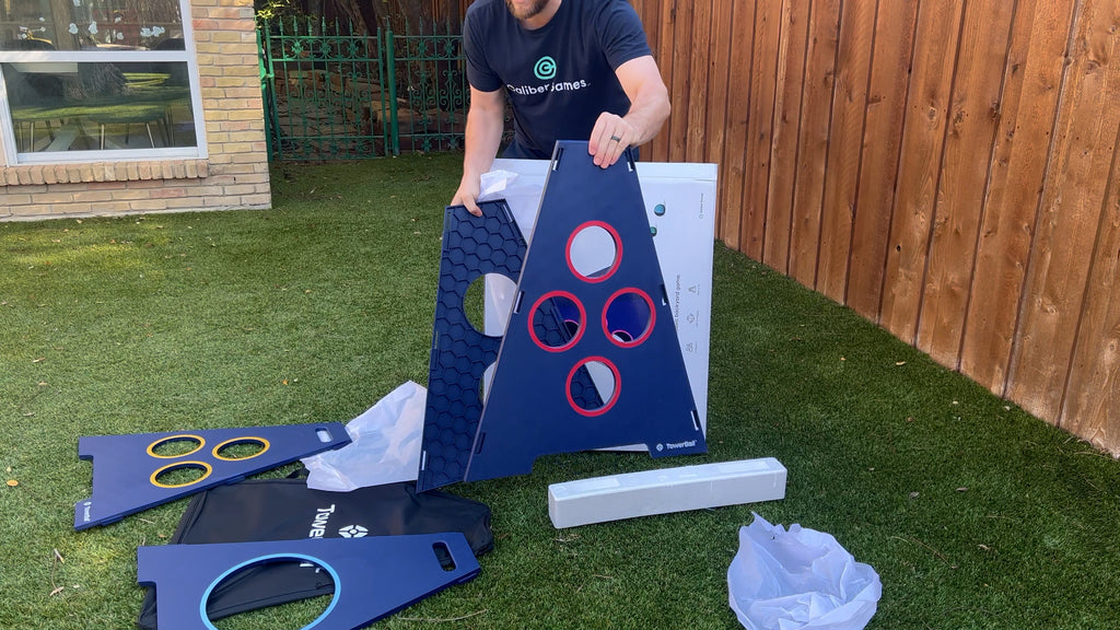 Man stands in backyard unboxing plastic TowerBall panels.