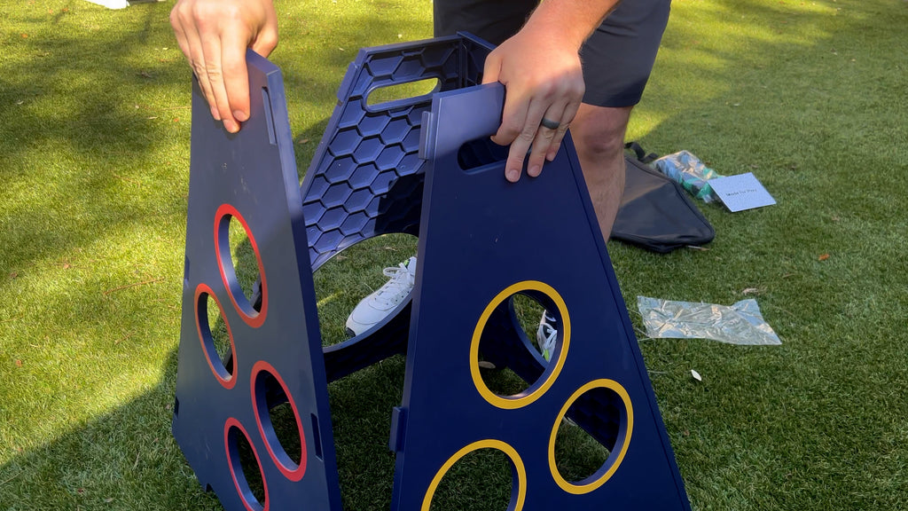 Person stands in backyard assembling TowerBall panels.