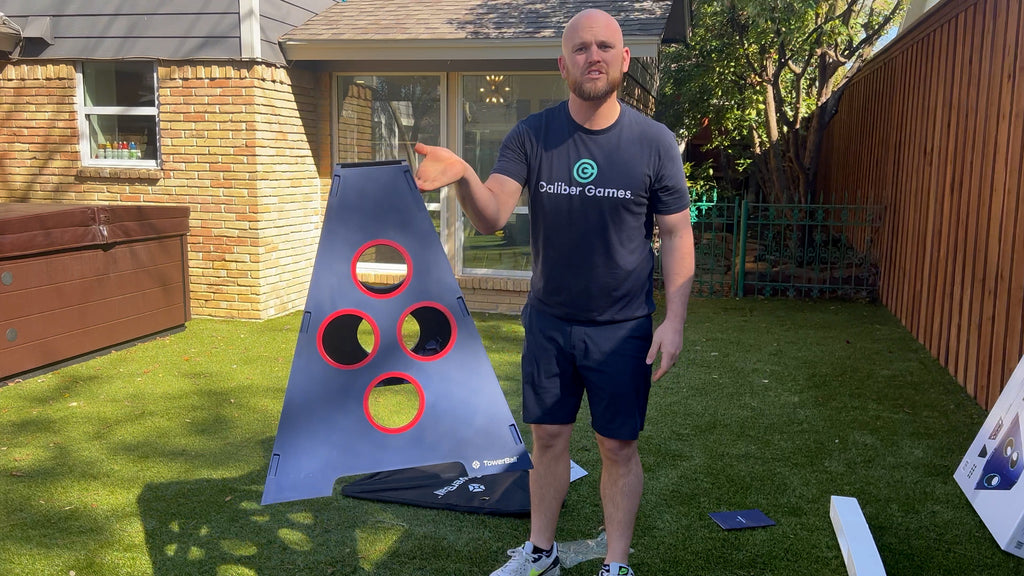 Man stands in backyard holding assembled TowerBall game discussing Towerball Review.