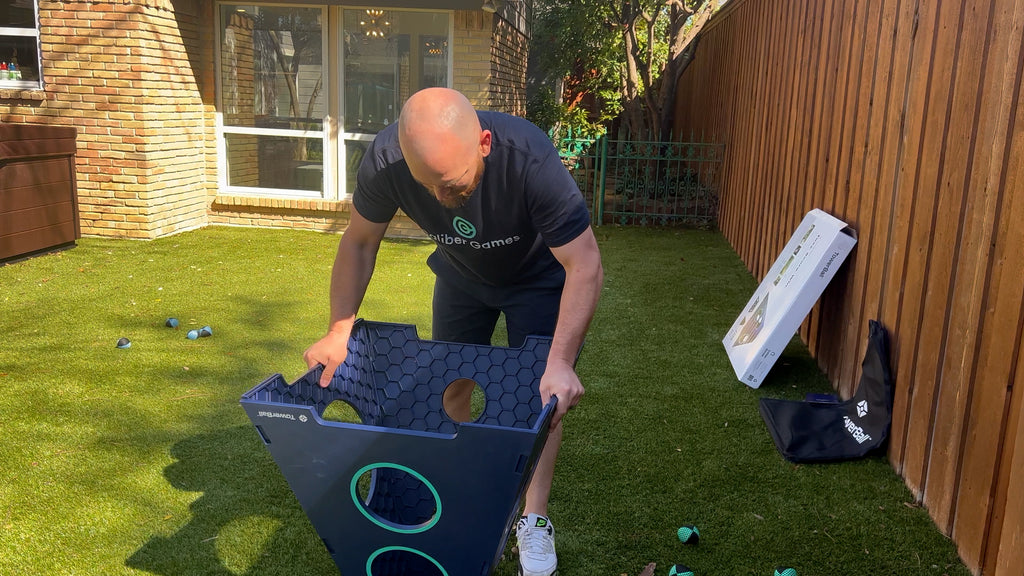 Man stands in backyard leaning over upsidedown TowerBall tower.